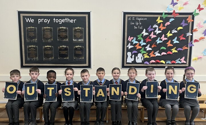 group of pupils holding letters spelling outstanding