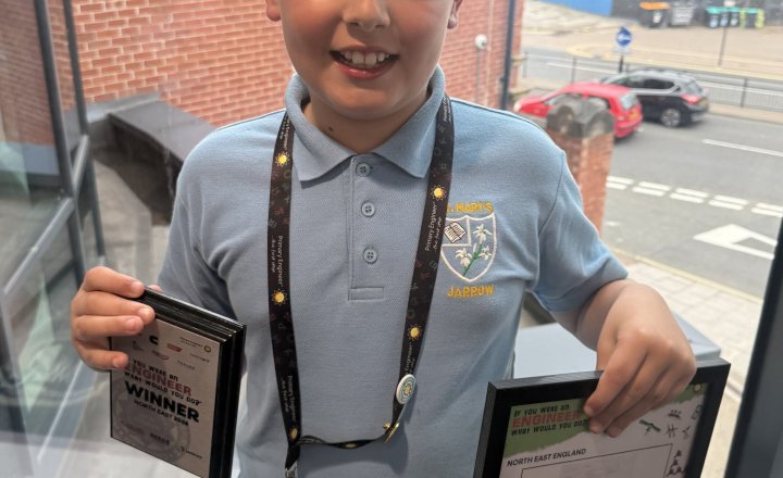 image shows joel a year 4 pupil holding framed copy of his design and his award