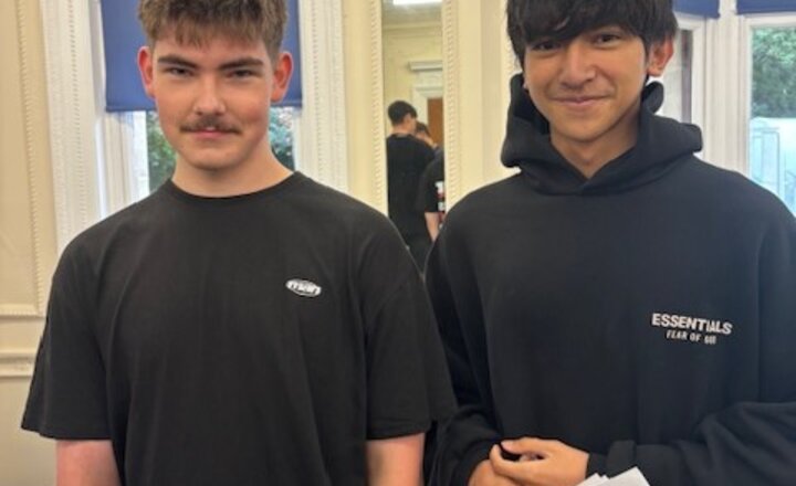 Two teenage boys smiling with their results in hand