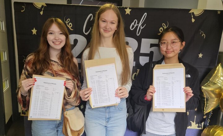 three teenage girls holding their results and smiling