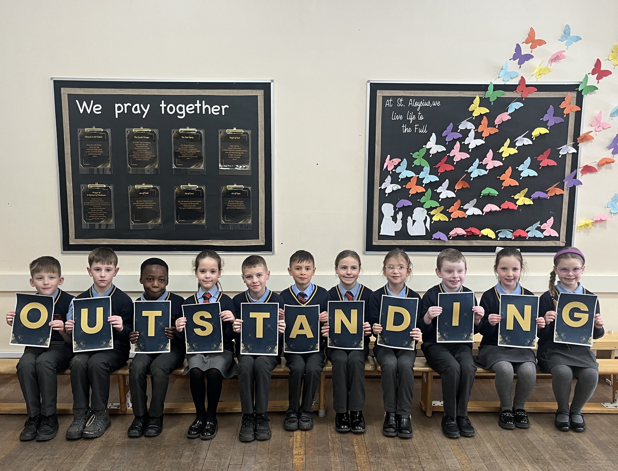 group of pupils holding letters spelling outstanding