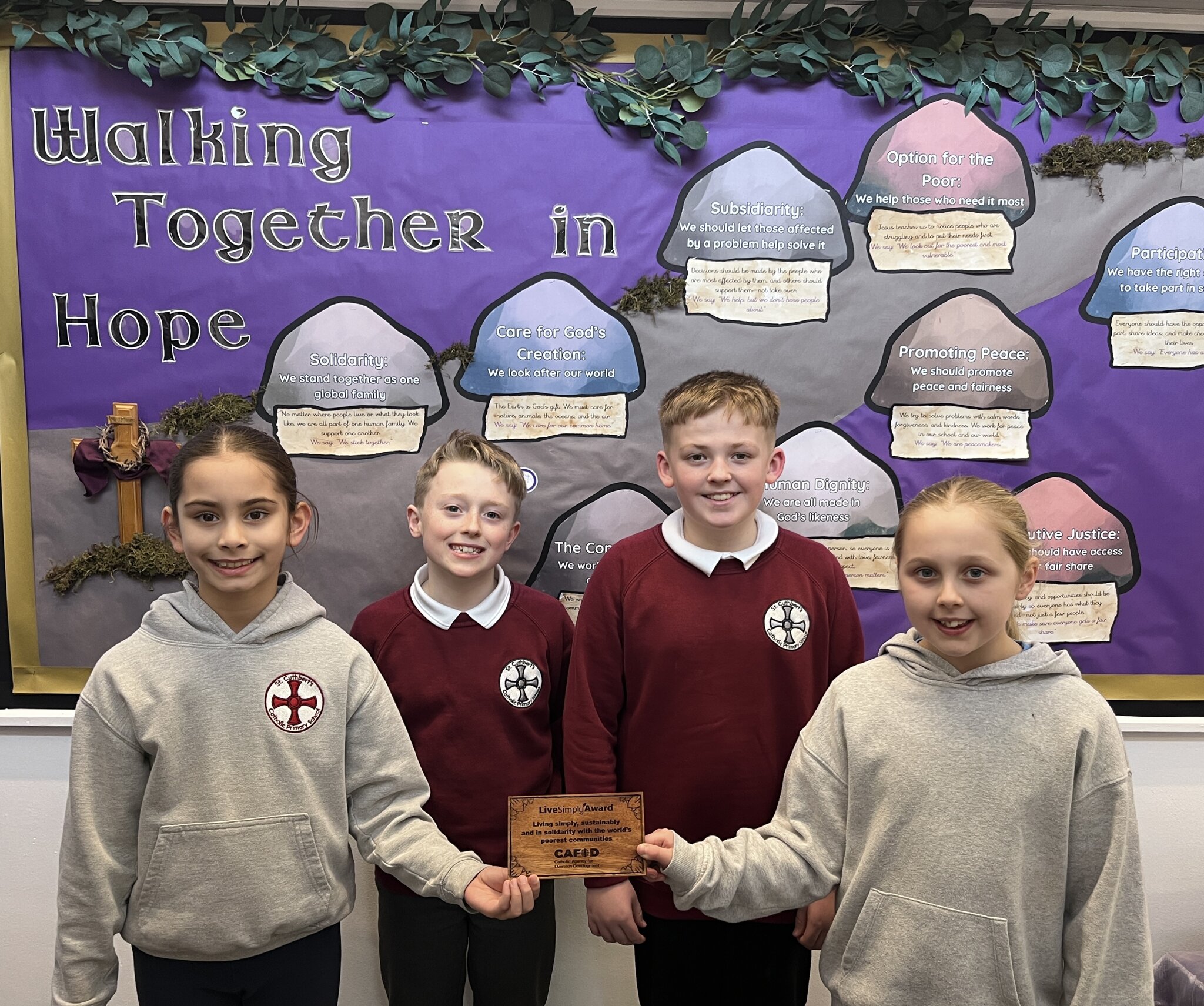 IMAGE OF FOUR PUPILS HOLDING THE LIVE SIMPLY AWARD