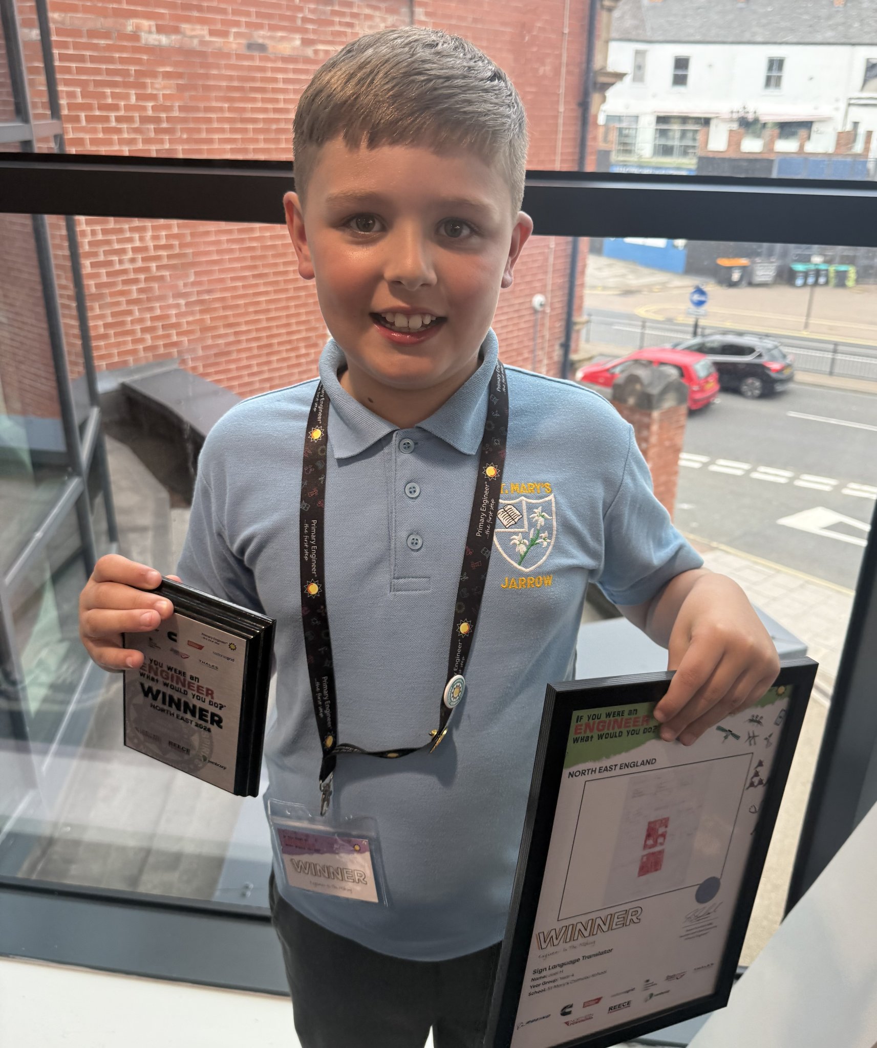 image shows joel a year 4 pupil holding framed copy of his design and his award