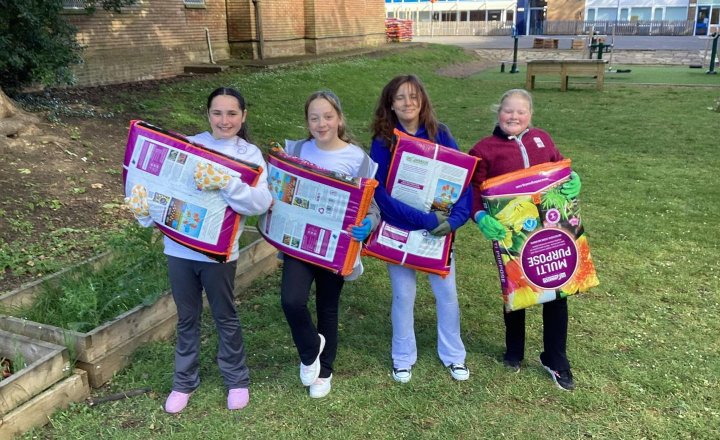 Pupils at Holy Family holding large bags of compost in preparation for Gardening Day