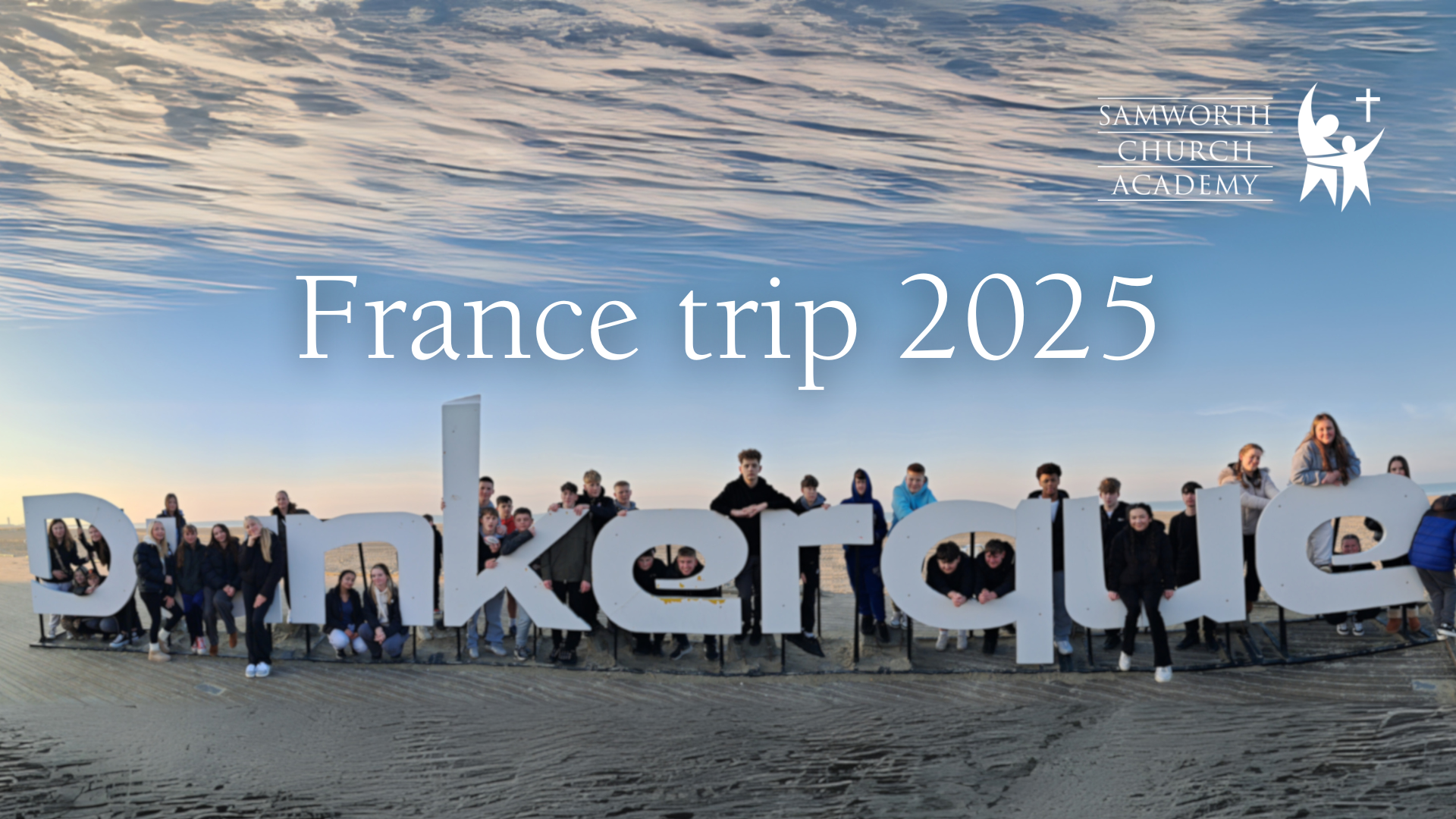 France Trip 2025 with students around a huge Dunkirk sign on the beach