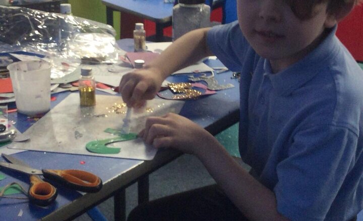 Image of Sebastian busy making Christmas crafts whilst singing Christmas songs, with a very happy Mrs Jones.