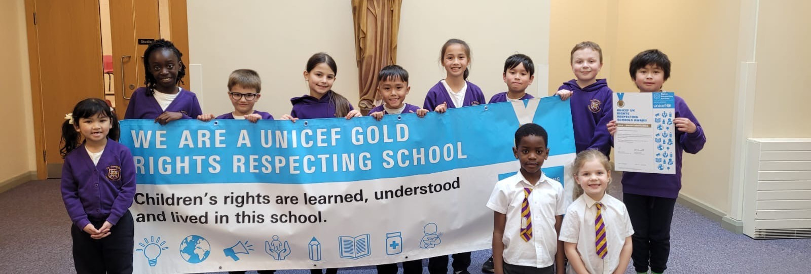 Group of school pupils holding the gold award banner