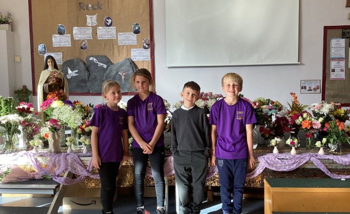 St Teresa's pupils infront of flowers and a statue of St Teresa to celebrate their feast day