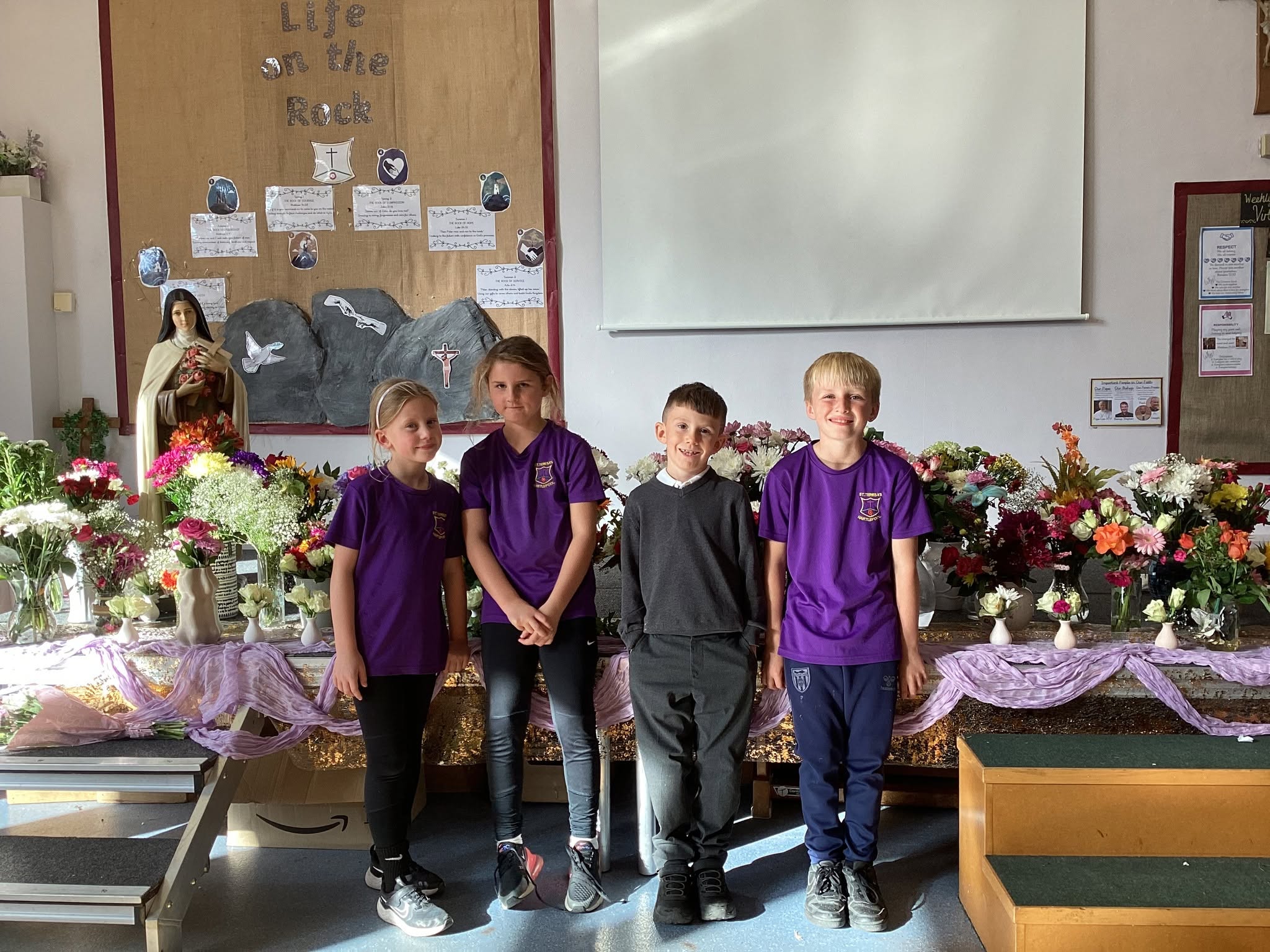 St Teresa's pupils infront of flowers and a statue of St Teresa to celebrate their feast day
